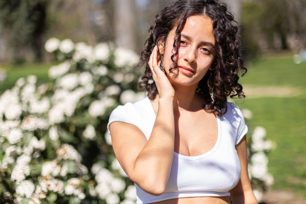 Jeune femme aux cheveux bouclés dans le parc profitant du soleil