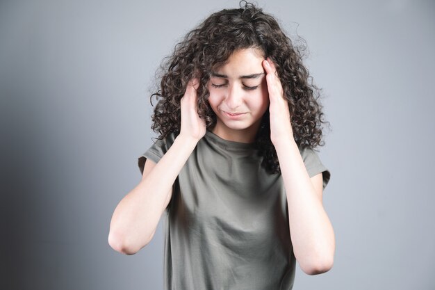 Jeune femme aux cheveux bouclés main dans la tête mal