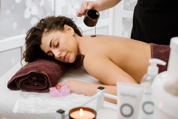 Une jeune femme aux cheveux bouclés prend des soins au chocolat au spa lors d'un massage dans un salon SPA