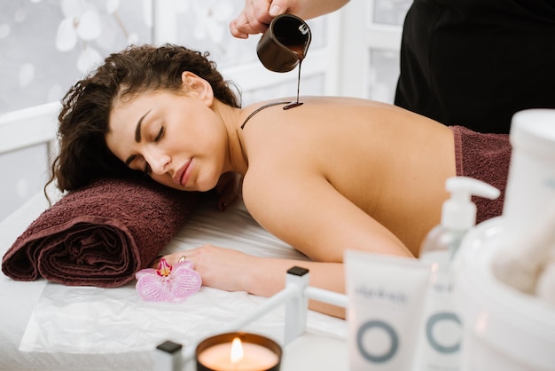 Une jeune femme aux cheveux bouclés prend des soins au chocolat au spa lors d'un massage dans un salon SPA