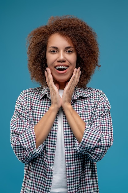 Jeune femme aux cheveux bouclés semblant satisfaite et souriante