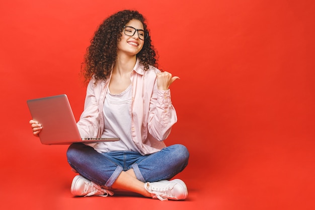 Jeune femme aux cheveux bruns bouclés avec ordinateur portable