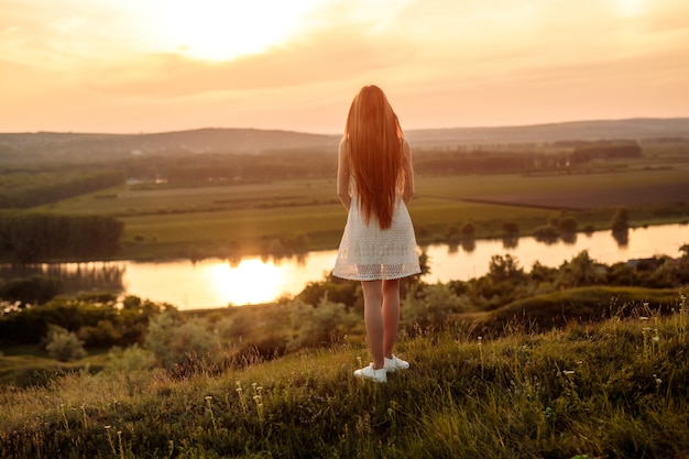 Jeune femme aux cheveux longs debout sur l'herbe