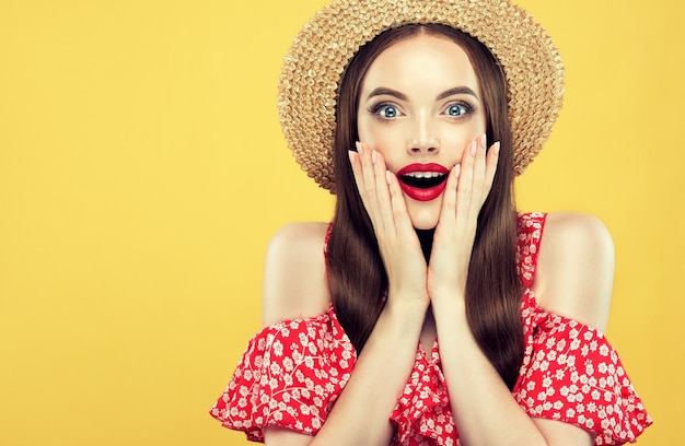 Une jeune femme aux cheveux longs étonnée, excitée et heureuse regarde les téléspectateurs avec surprise.