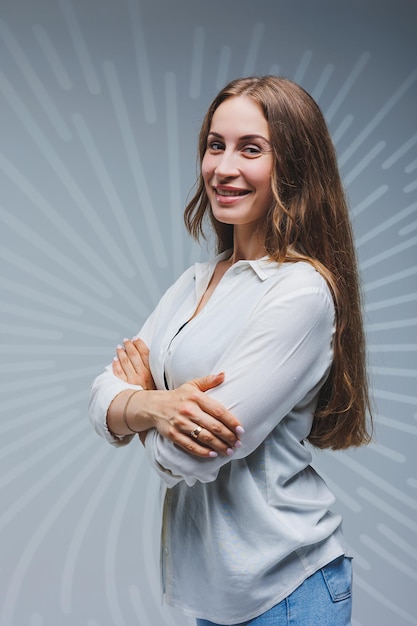 Jeune femme aux cheveux longs en jeans et une chemise blanche sur un fond uni Émotions sur le visage d'une femme