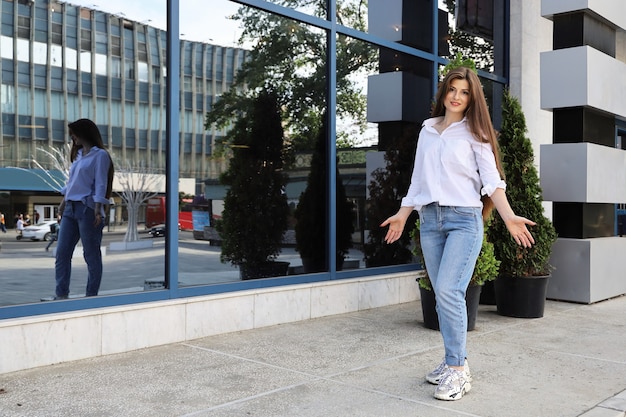 Jeune femme aux cheveux longs se tient près du bâtiment vitré