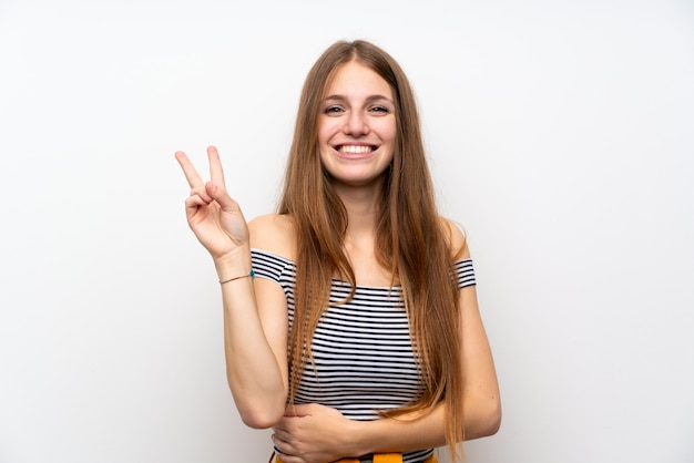 Jeune femme aux cheveux longs, souriant et montrant le signe de la victoire