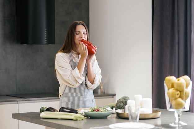 Jeune femme aux cheveux longs tenant le poivron rouge dans les mains