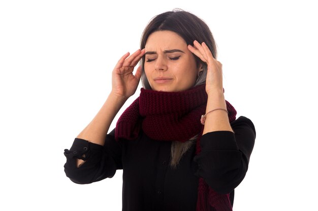 Jeune femme aux cheveux noirs en chemisier noir avec une longue écharpe ayant un mauvais mal de tête sur fond blanc en studio