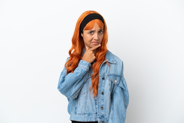 Jeune femme aux cheveux orange isolé sur fond blanc ayant des doutes