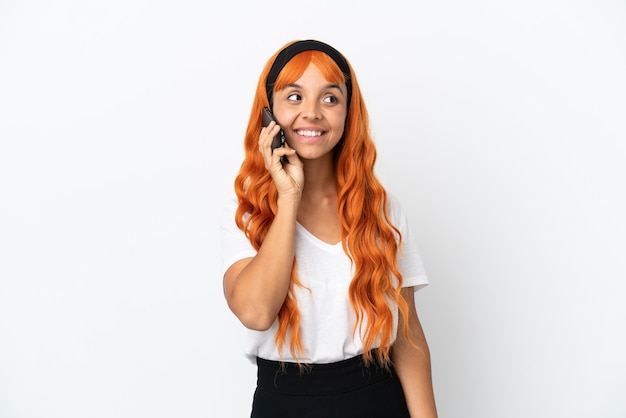 Jeune femme aux cheveux orange isolé sur fond blanc en gardant une conversation avec le téléphone mobile