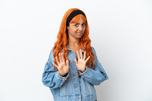 Jeune femme aux cheveux orange isolé sur fond blanc nerveux s'étendant les mains vers l'avant