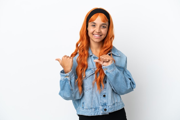 Jeune femme aux cheveux orange isolé sur fond blanc pointant sur le côté pour présenter un produit