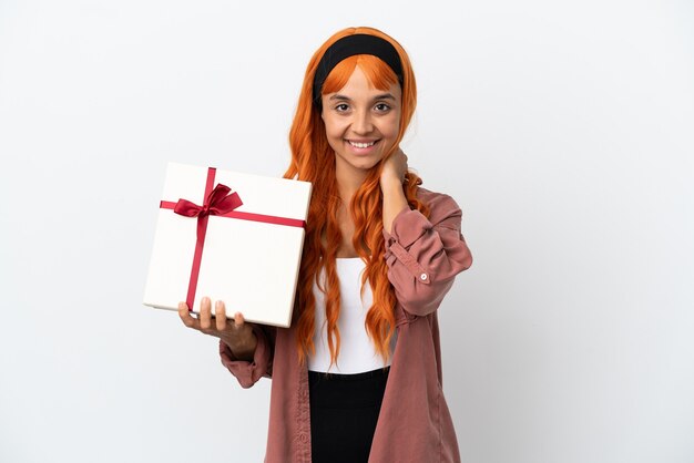 Jeune femme aux cheveux orange tenant un cadeau isolé sur fond blanc en riant