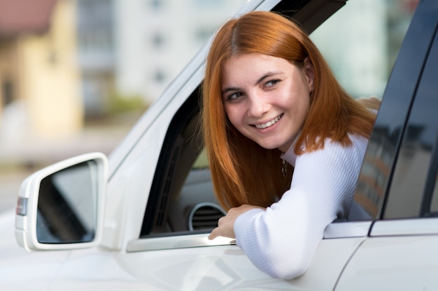 Jeune femme aux cheveux rouges au volant d'une voiture.