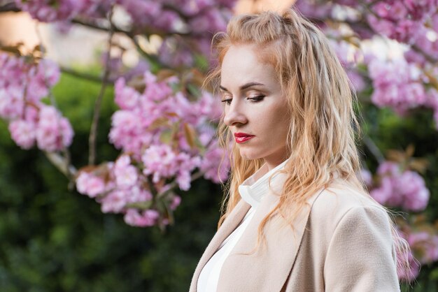 Une jeune femme aux cheveux roux contre un arbre en fleurs Portrait d'une jolie fille blonde sur fond de printemps en plein air