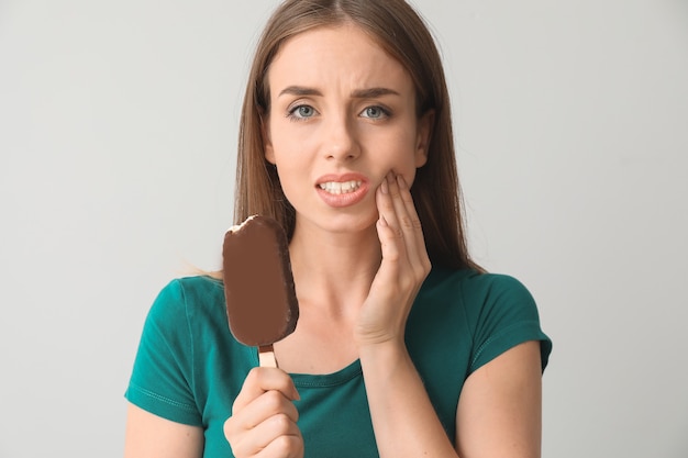 Jeune femme aux dents sensibles et glace froide sur fond gris