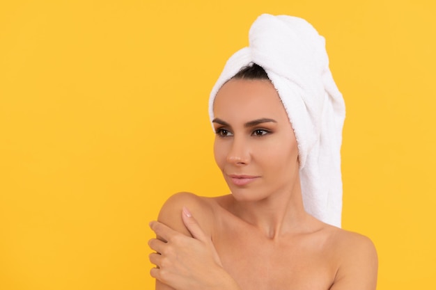 Jeune femme aux épaules nues après la douche sur fond jaune