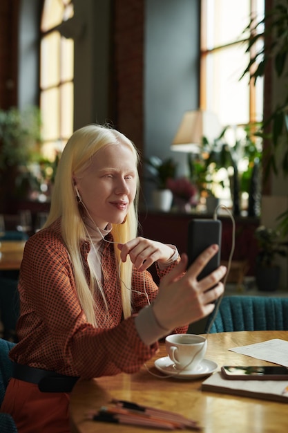 Jeune femme aux longs cheveux blonds regardant l'écran du smartphone