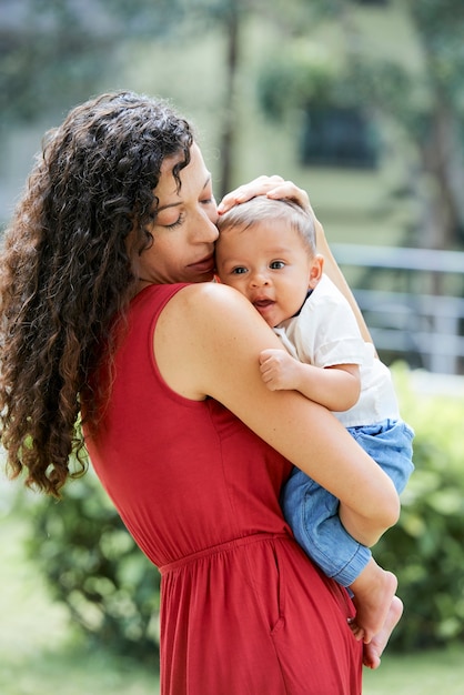 Jeune femme aux longs cheveux bouclés tenant son petit fils et lui caressant doucement la tête