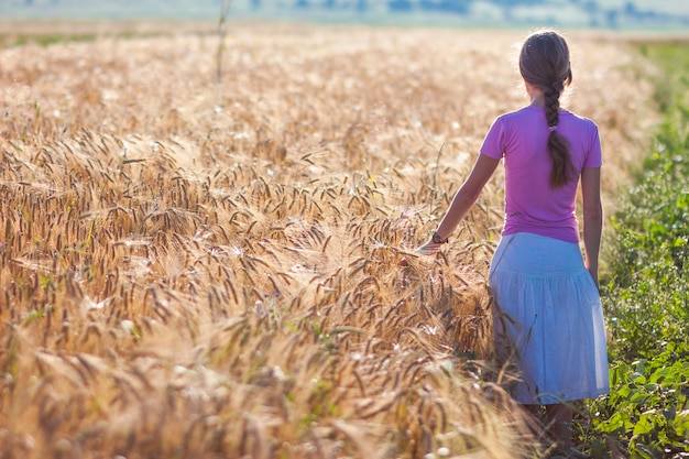 Jeune femme aux longs cheveux bruns se tenant dans le champ de blé.