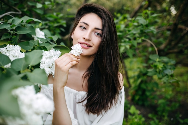 Jeune femme aux longs cheveux noirs avec une fleur lilas blanc