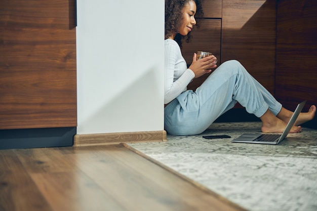 Jeune femme aux pieds nus rêveuse aux cheveux bouclés assis sur le sol