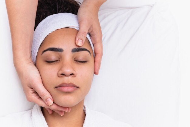 Jeune femme aux sourcils épais et peau parfaite sur fond blanc, concept photo de beauté, soins de la peau, concept spa, traitement, massage facial.