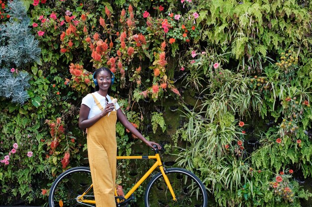 Jeune femme ayant une glace sur un vélo avec un jardin vertical en arrière-plan Concept de style de vie en plein air