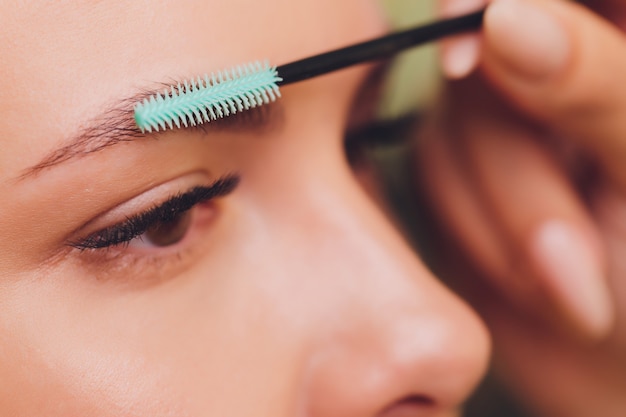 Photo jeune femme ayant une procédure de correction des sourcils professionnelle dans un salon de beauté.