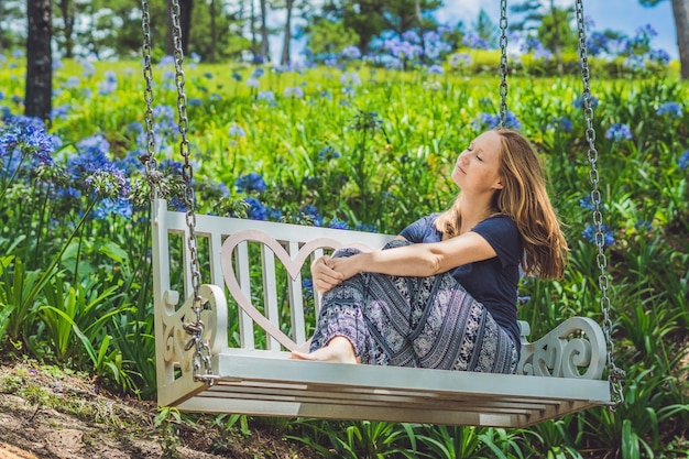 Jeune femme sur une balançoire dans un jardin fleuri