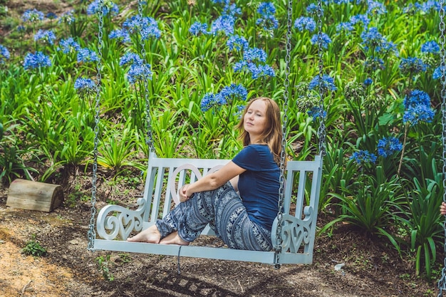 Jeune femme sur une balançoire dans un jardin fleuri
