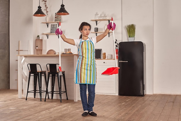 Jeune femme balayant le sol sur la cuisine