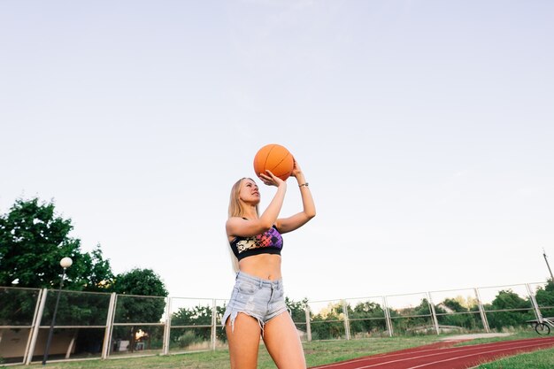 Jeune femme avec un ballon de basket sur un terrain de basket extérieur