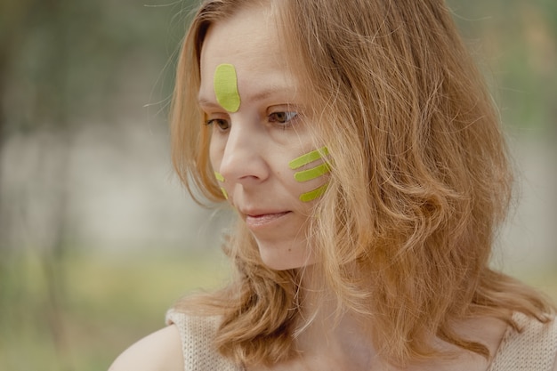 Jeune femme avec des bandes vertes sur le visage Taping esthétique du visage