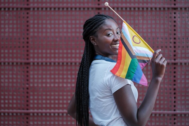 Une jeune femme avec une bannière LGBT souriante et luttant pour la fierté Concept de drapeau arc-en-ciel