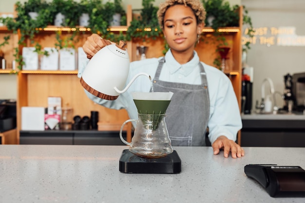 Jeune femme barista aux cheveux courts préparant du café avec un filtre au comptoirx9xA