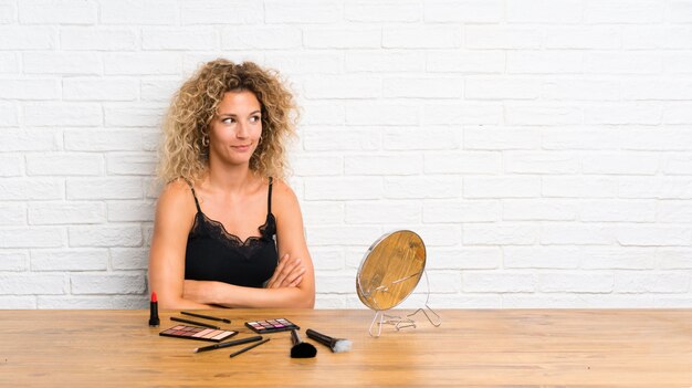 Jeune femme avec beaucoup de pinceau de maquillage dans une table debout et regardant sur le côté