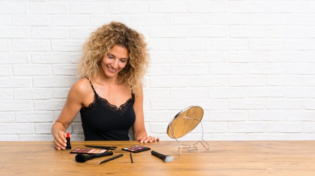 Jeune femme avec beaucoup de pinceau de maquillage dans une table