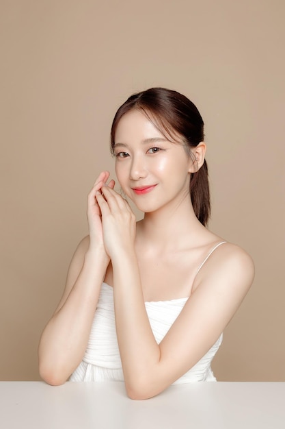Jeune femme de beauté asiatique a tiré les cheveux en arrière avec un style de maquillage coréen sur le visage et une peau parfaite sur fond rose isolé Traitement du visage Cosmétologie chirurgie plastique