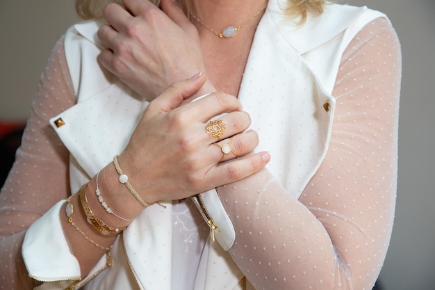 Jeune femme avec de beaux bijoux en or en gros plan dans des vêtements de mode blancs