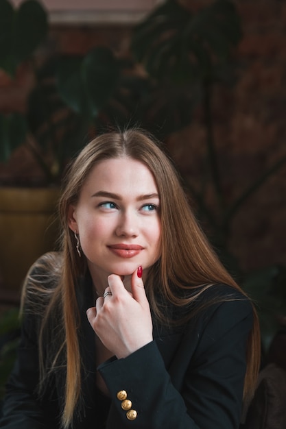 Jeune femme avec de beaux cheveux longs et des yeux attrayants se prélasser dans un café