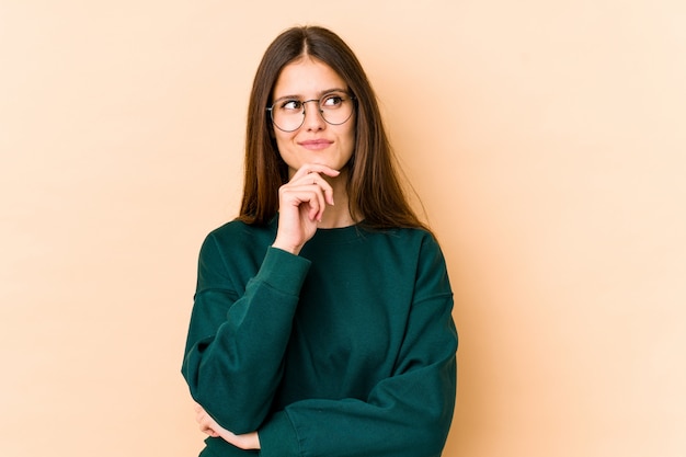 Jeune femme sur beige à côté avec une expression douteuse et sceptique.