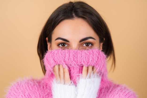 Jeune femme sur beige dans un pull tricoté confortable multicolore lumineux mignon souriant