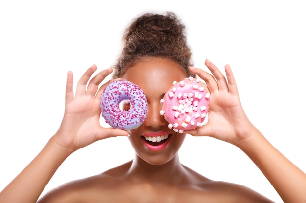 Jeune femme avec des beignets savoureux sur fond blanc