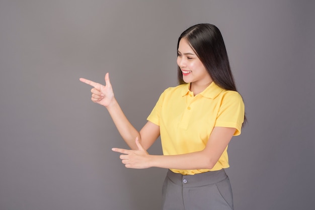 Jeune femme belle confiante portant une chemise jaune est sur studio gris