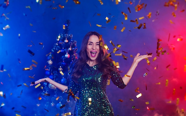 Jeune femme belle excitée souriante près de l'arbre de Noël