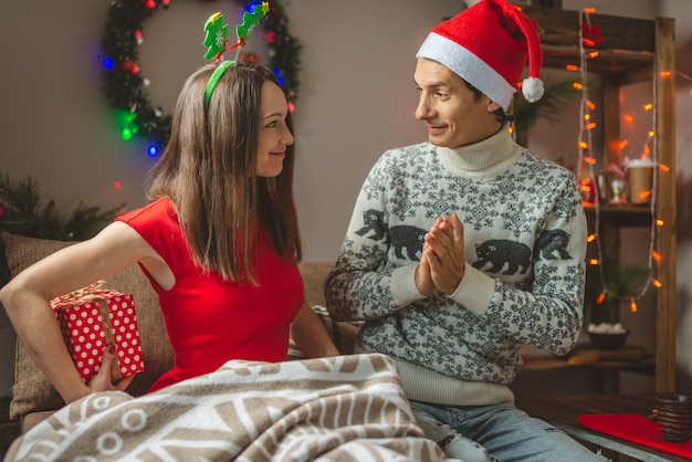 Jeune femme belle femme donne à son mari une boîte cadeau surprise