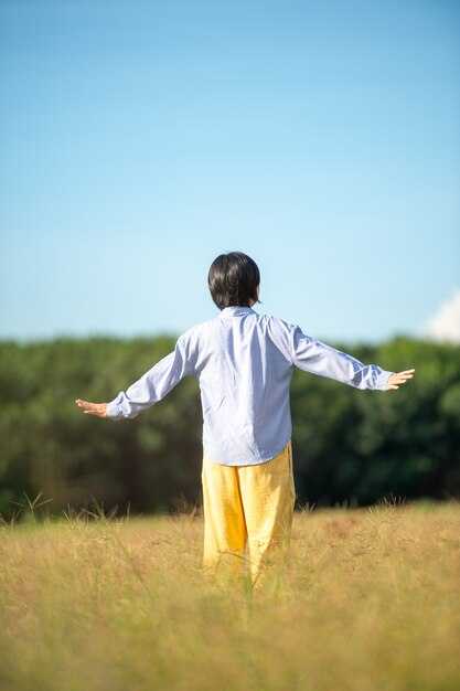 Jeune femme belle femme heureuse à la belle prairie au fond de ciel. notion de bonheur.