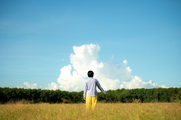 Jeune femme belle femme heureuse à la belle prairie au fond de ciel. notion de bonheur.